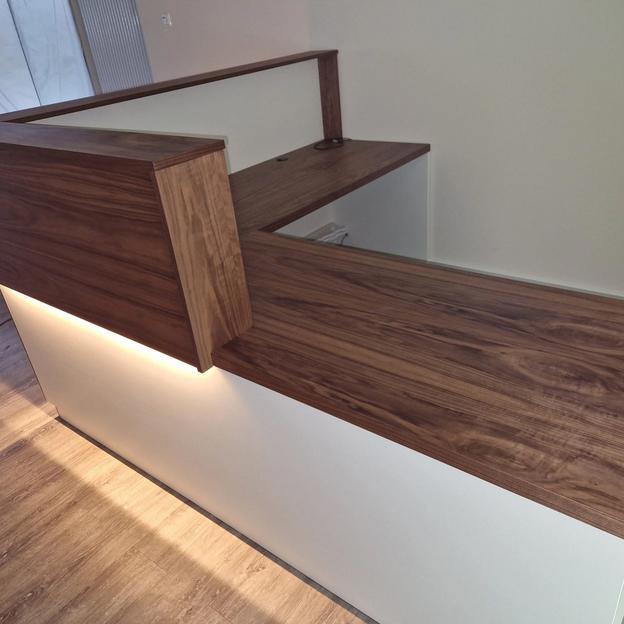 Funktionaler Empfangstresen mit Holzaufsatz, Arbeitsfläche und integriertem Kabeldurchlass.