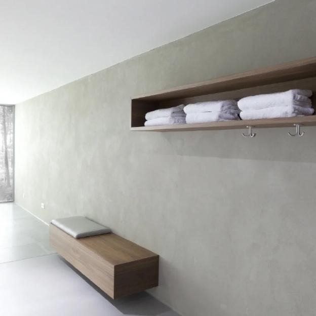 Moderner Umkleidebereich mit schwebender Holzbank, Wandregal und gefalteten Handtüchern.
