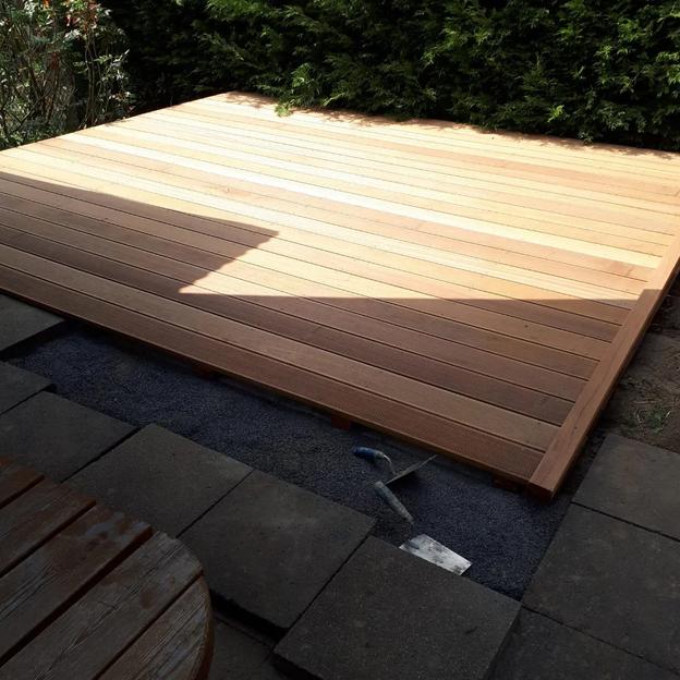 Neu gebaute Holzterrasse mit sauber verlegten Dielen und angrenzender Steinfläche.