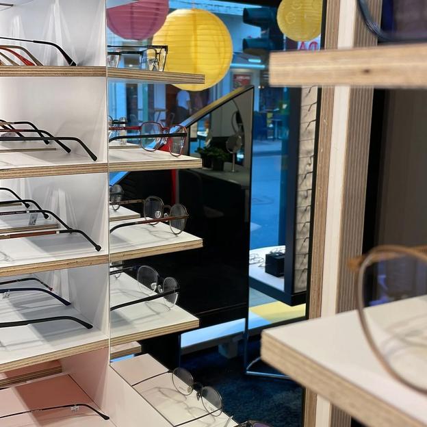 Modernes Brillenregal mit Glasgestellen in optischem Fachgeschäft für Brillenpräsentation.