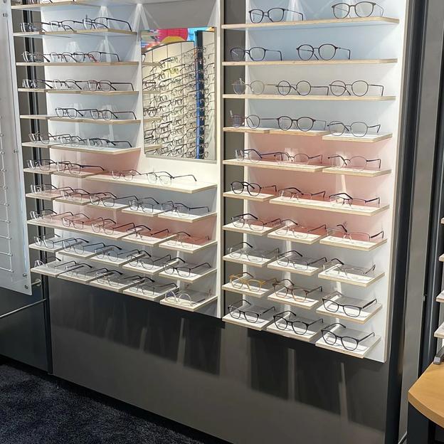 Große Brillenwand mit vielen Brillengestellen, modern gestaltet für Optikgeschäft.