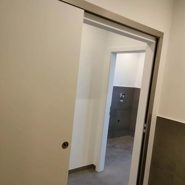 Geöffnete weiße Schiebetür mit modernem Rahmen, Durchgang in angrenzenden Raum.