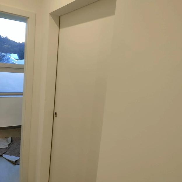 Dezente weiße Schiebetür in moderner Wand eingelassen, platzsparend im Innenbereich.