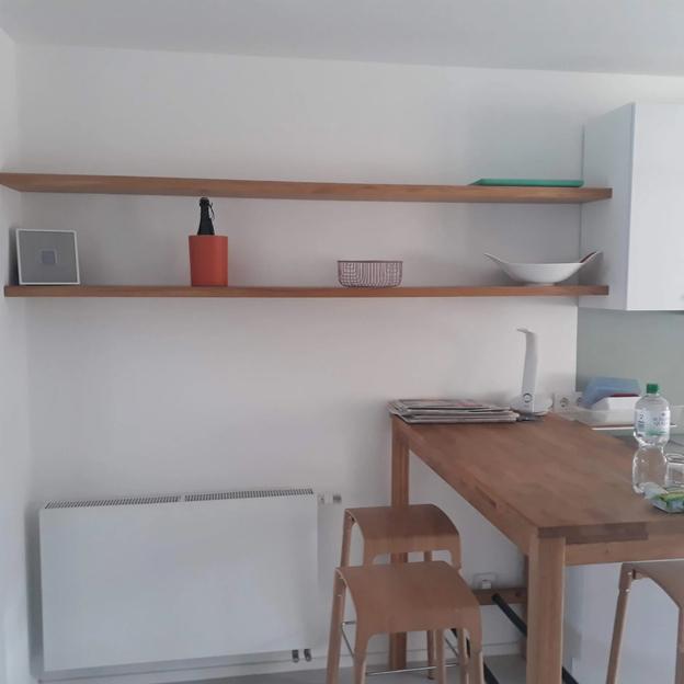 Wandregale aus Holz in Küche, dekoriert mit Geschirr, Pflanzen und Alltagsgegenständen.