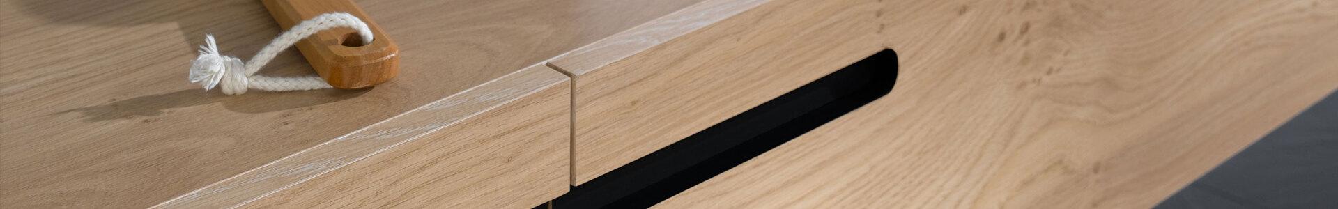 Detailaufnahme eines schmalen Waschtischunterschrankes aus Massivholz mit eingelassenen Griffen