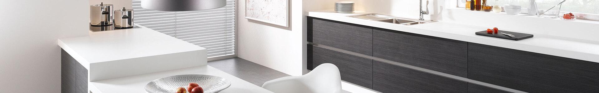 Impression einer einzeiligen Küchengestaltung in schwarz-weiß mit Esstisch für Zwei