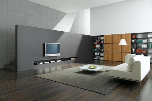 Offene Wohnraumimpression mit grauer TV-Trennwand zur Treppe und Einbauregal aus Holz und weißem Sofa