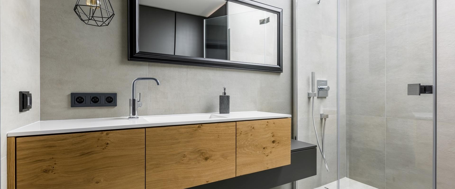 Asymmetrischer Waschtisch mit Schubläden in Echtholz und schwarzer Lackierung auf weiterem schmalen Unterschrank.