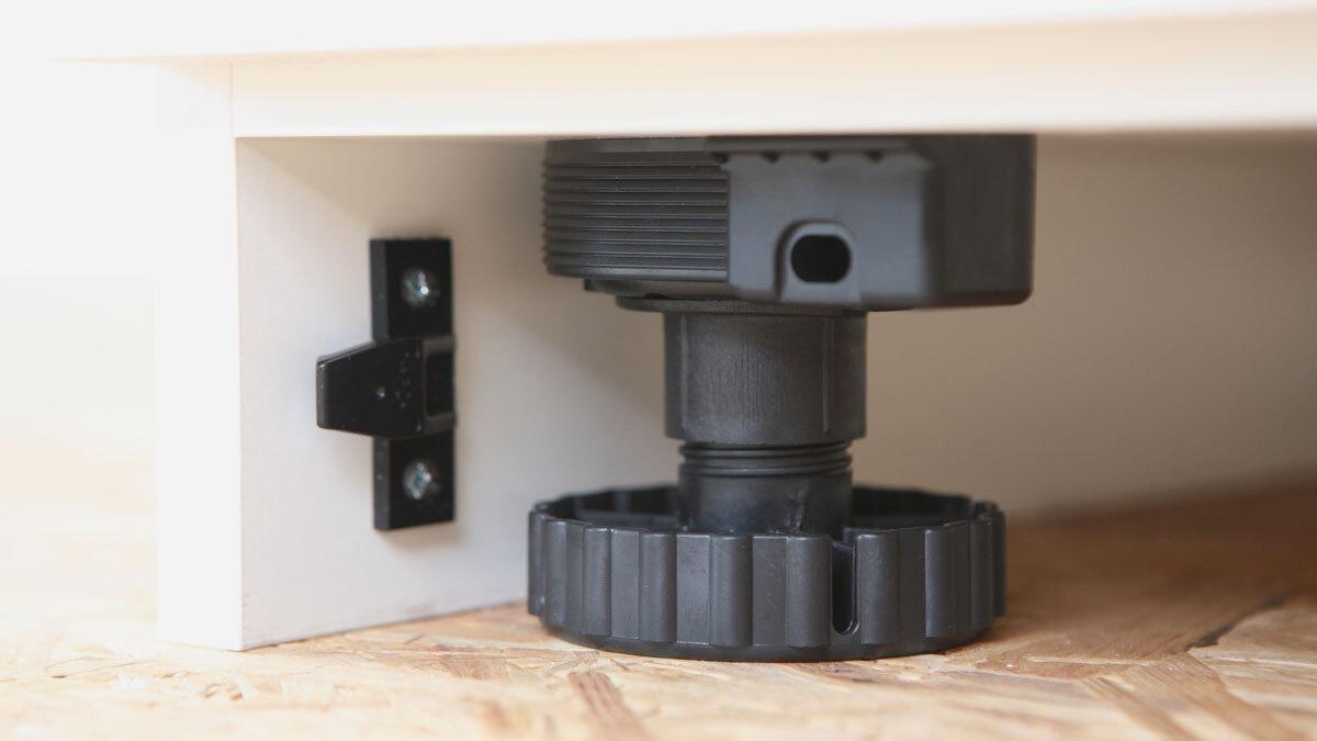 Detailaufnahme eines verstellbaren schwarzen Bodensockels mit Schraubmechanismus