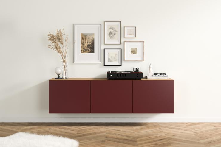 Modernes Hängeboard nach Maß im Wohnraum Elegantes, burgunderrotes Hängeboard nach Maß mit glatten Fronten und Holzakzenten, angebracht unter einer kunstvollen Bildergalerie im Wohnzimmer.